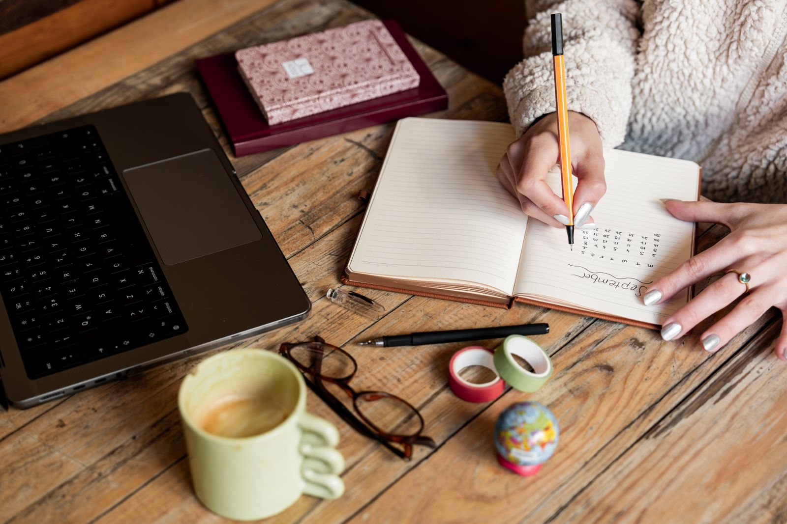 A trader writes down her trades in a notebook next to her laptop