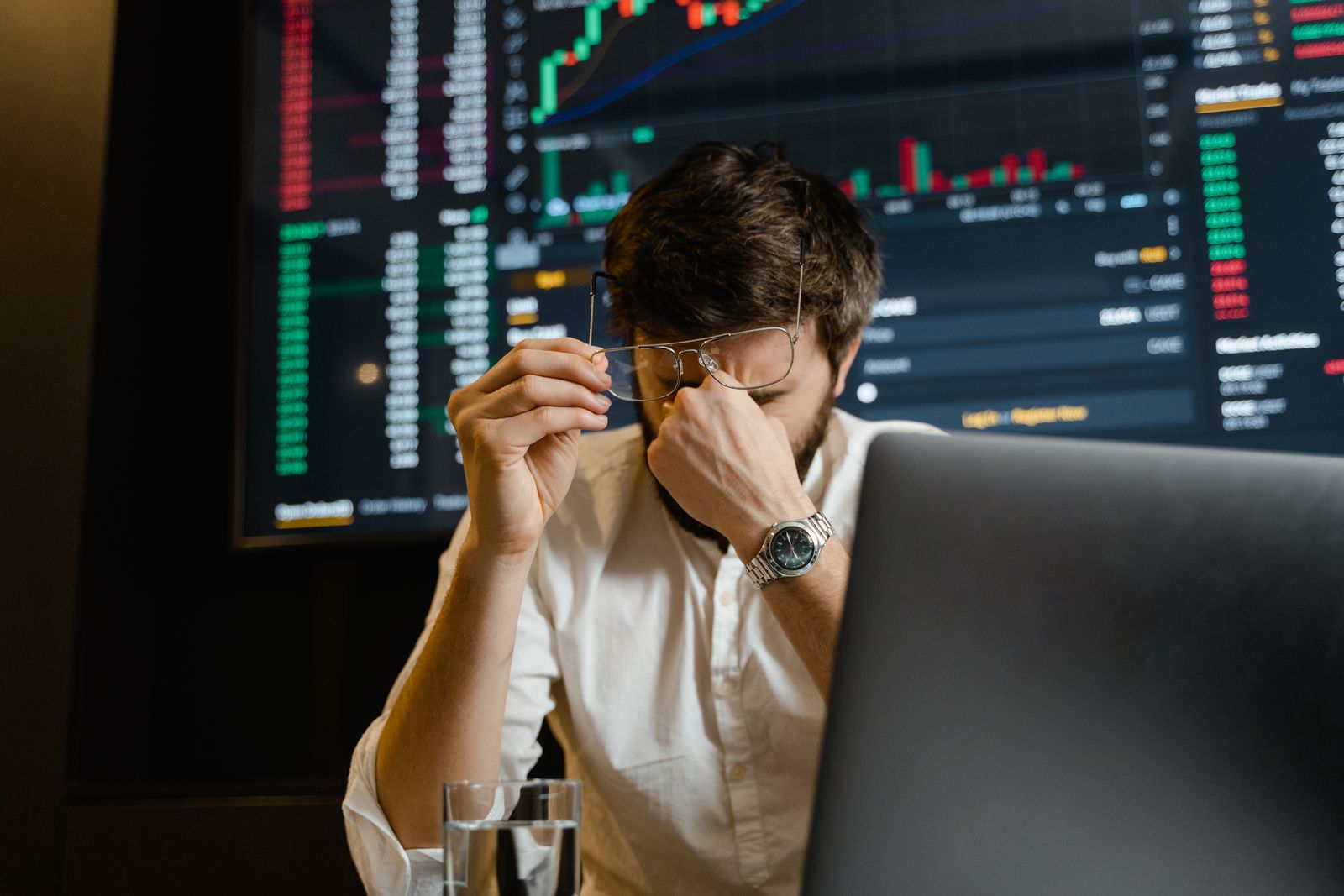 Un trader se pince l'arête du nez devant ses écrans après une perte
