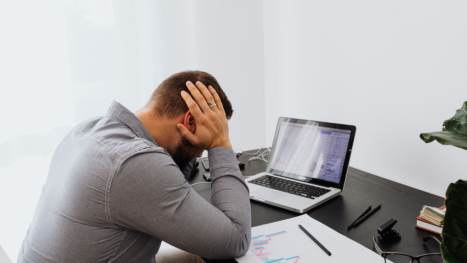 Un trader la tête entre les mains devant un écran de cotations